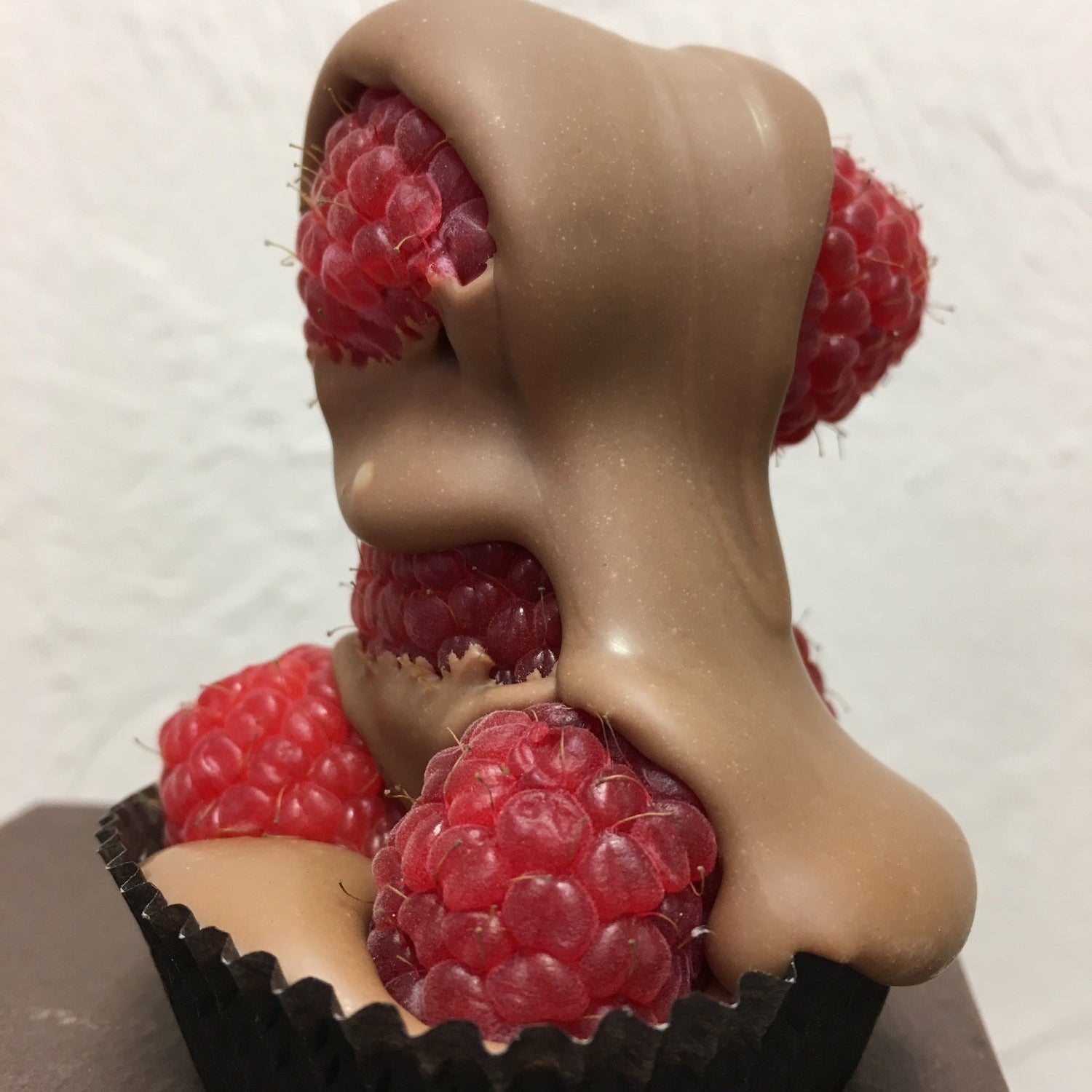 raspberries drizzled with milk chocolate against a neutral background